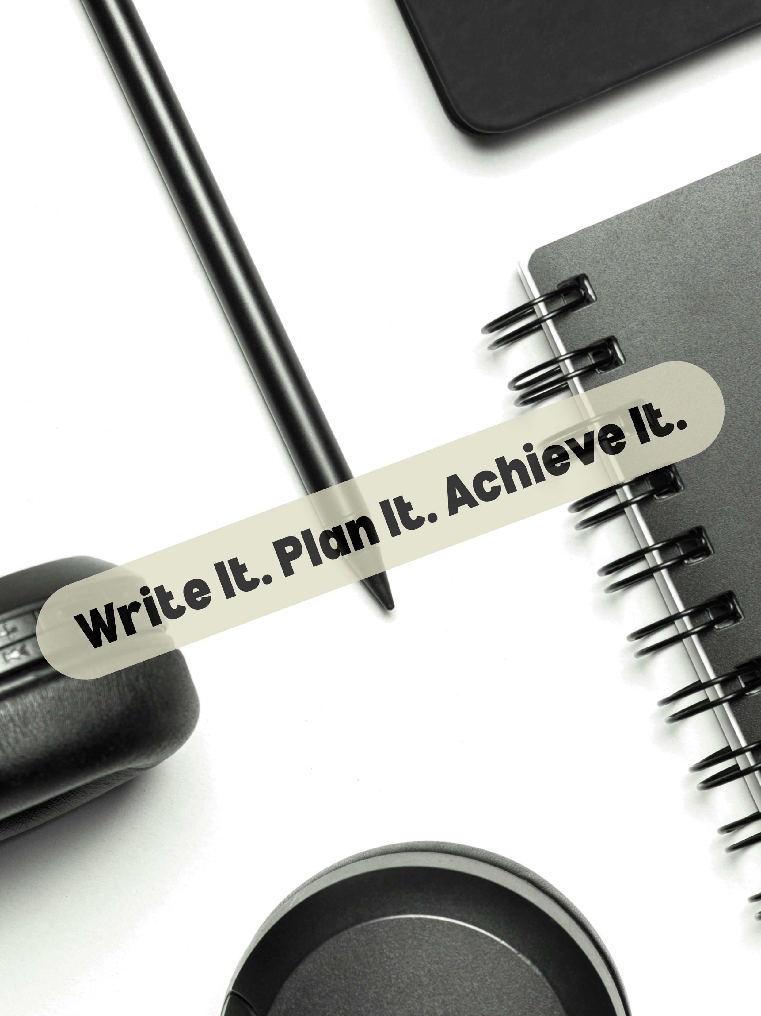 Motivational flat lay with spiral notebook, pen, and headphones featuring 'Write It. Plan It. Achieve It.' quote for goal setting and productivity