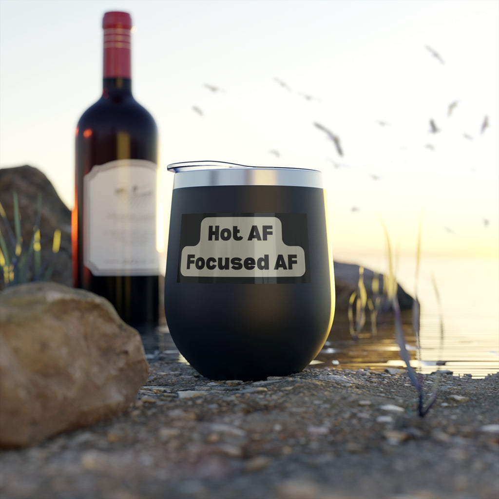 Black tumbler with 'Hot AF Focused AF' text next to a bottle of red wine