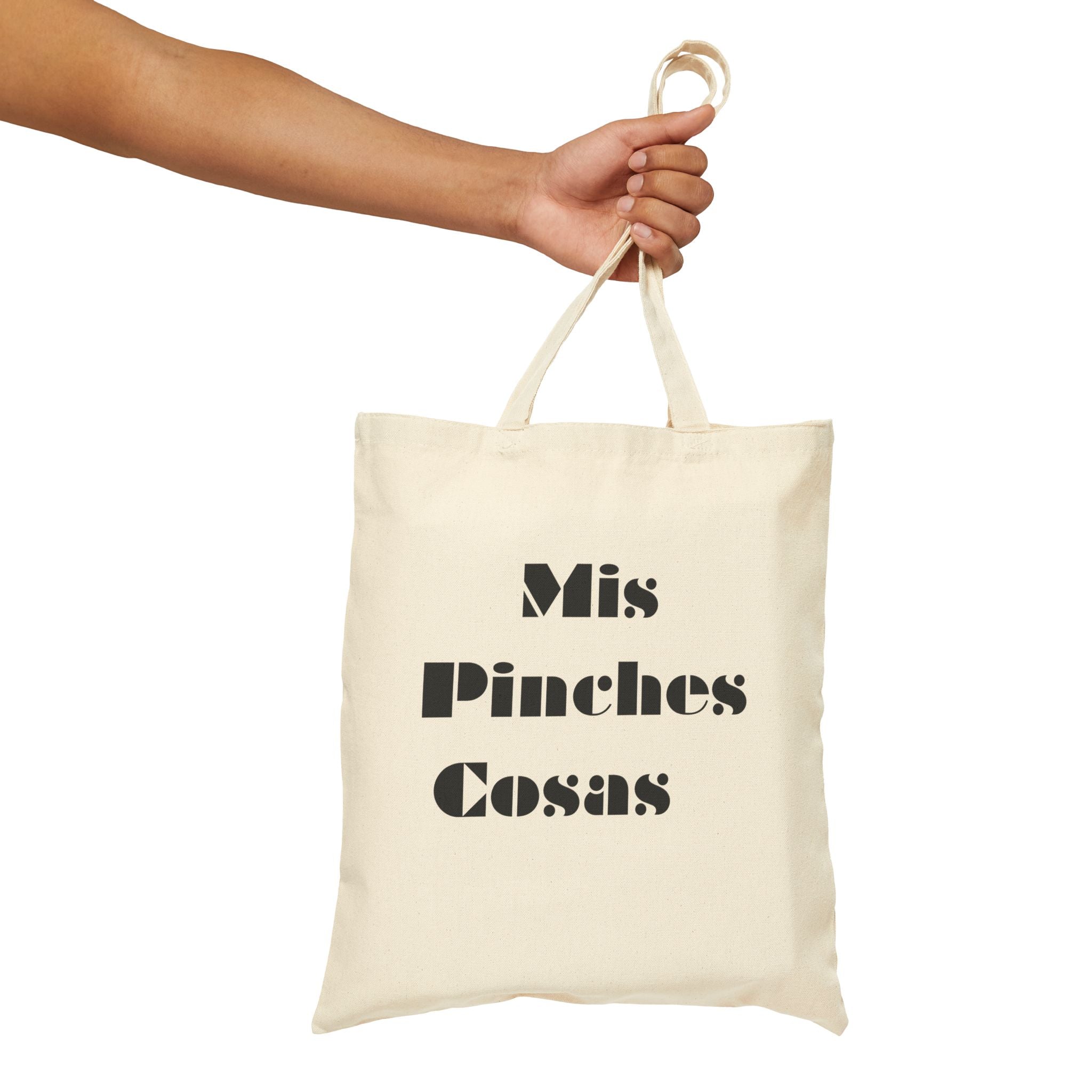 Beige tote bag with black text held by a hand on a white background